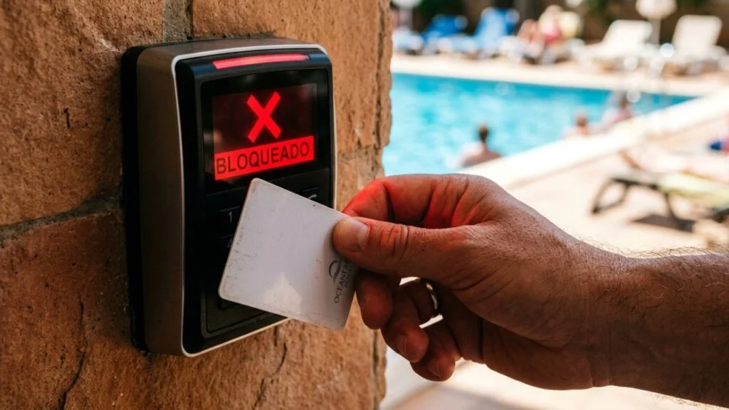 inadimplência condomínio - leitor de acesso exibindo tela bloqueada em vermelho com piscina ao fundo